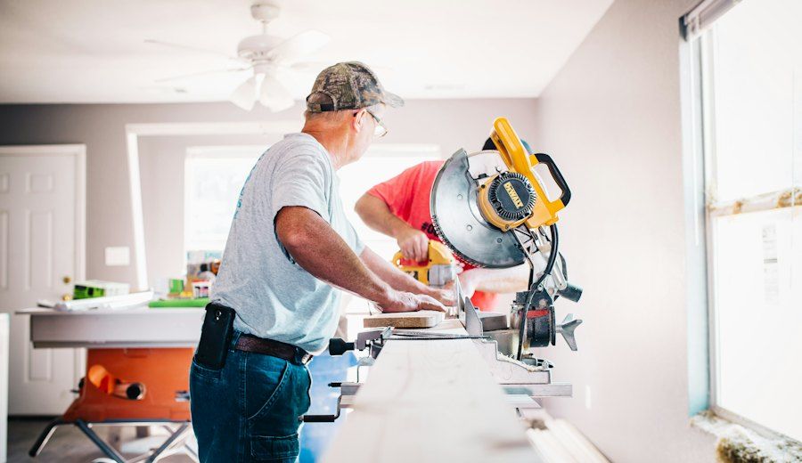 Due artigiani al lavoro con la troncatrice